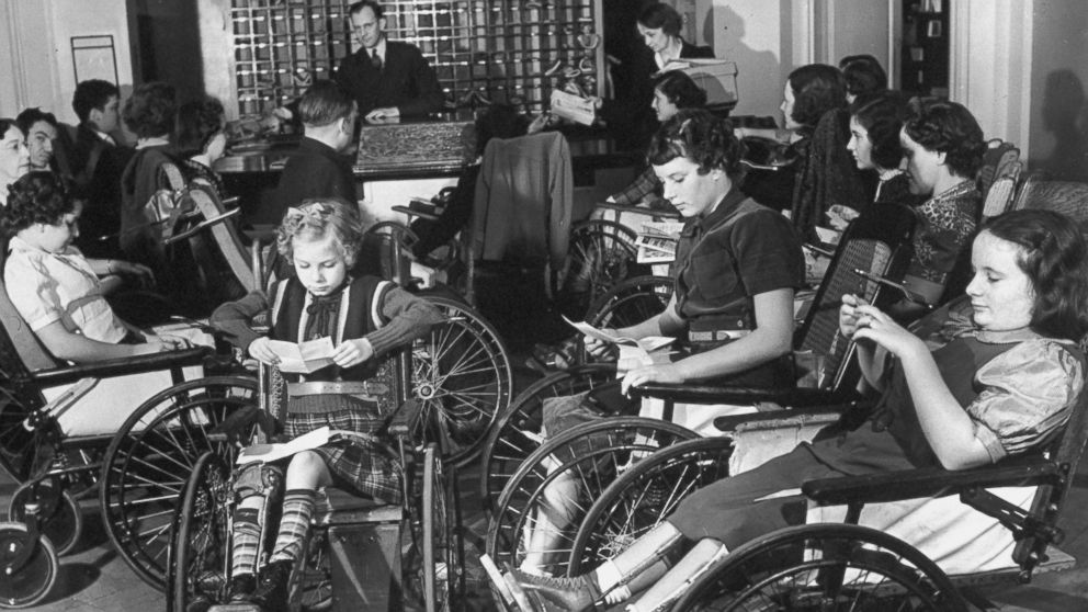 Crianças e adolescentes com pólio lendo cartas dos familiares de quem ficam afastados durante tratamento no Instituto de Reabilitação em Warm Springs, nos EUA, fundado por Franklin D. Roosevelt. O 32º presidente dos Estados Unidos teve poliomielite e usava cadeira de rodas.